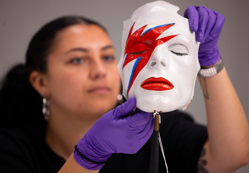 A V&A Collections Access Officer handles a life mask by William Forsche of David Bowie’s face painted to resemble his makeup from Aladdin Sane